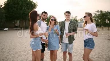 一群朋友在<strong>日</strong>落时分在海滩上玩着享受饮料和放松的乐趣。 男女<strong>青年</strong>